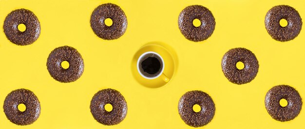 Ciambella con glassa al cioccolato e tazza di caffè sullo sfondo giallo Banner Flat lay Pattern