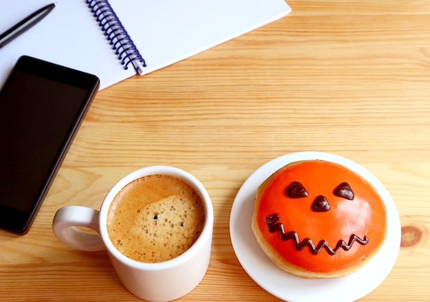 Ciambella di Halloween dai colori vivaci e caffè caldo su una scrivania
