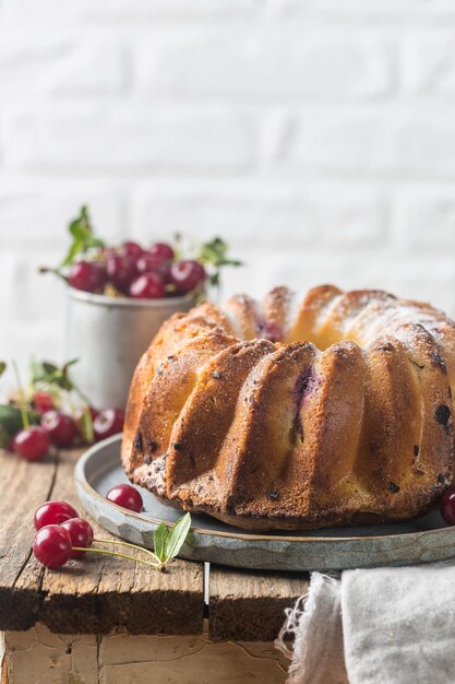 Ciambella fresca fatta in casa con ciliegia su tavola di legno