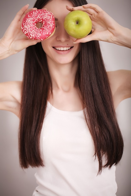 Ciambella rosa disponibila della tenuta della donna esile e mela verde