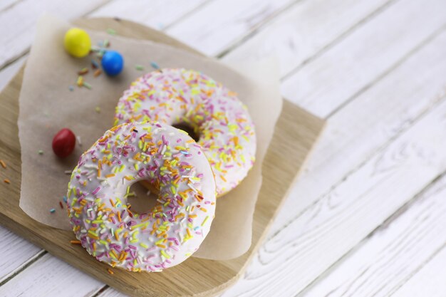 Ciambella su uno sfondo di legno bianco e una manciata di dolci ornamenti