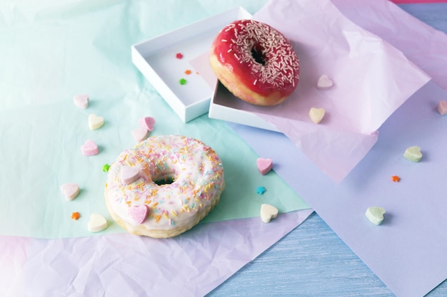 Ciambelle appena sfornate glassate con varie sfumature di rosa e cosparse di cuori di caramello