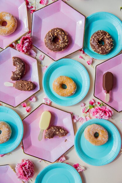 Ciambelle e gelato su piatti con petali di dianthus