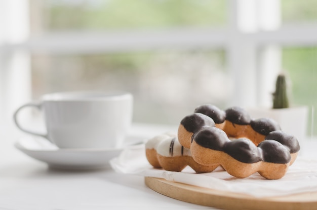 Ciambelle e tazza di caffè su una tavola di legno bianca