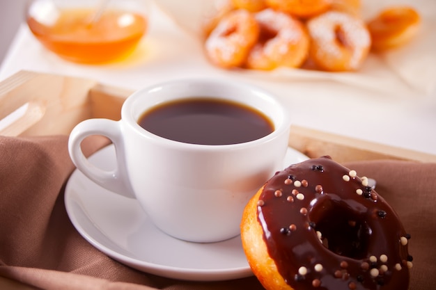 Ciambelle fresche con la tazza di caffè sulla tavola di legno