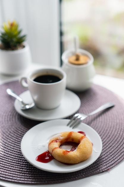 Ciambelle fresche di zucchero a velo con cioccolato e tazza di caffè sul tavolo di legno nella caffetteria