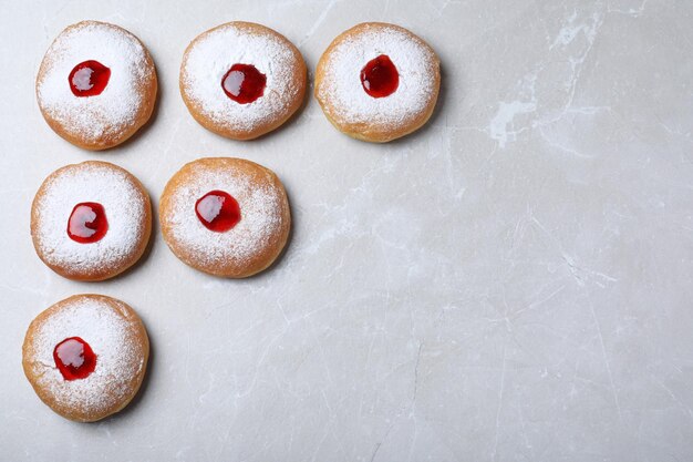 Ciambelle Hanukkah con gelatina e zucchero in polvere su tavola grigia piatta Spazio per il testo