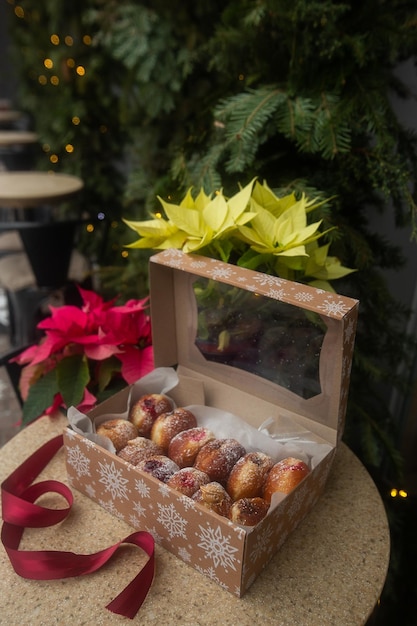 Ciambelle tedesche Berliner con ripieno e zucchero a velo in una scatola su un tavolo di pietra marrone su sfondo di decorazioni natalizie