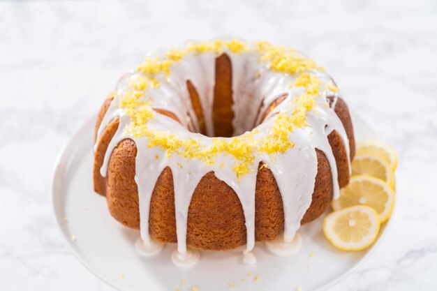 Ciambellone al limone decorato con scorza di limone su un supporto per dolci.