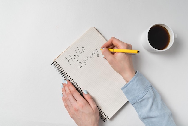 Ciao primavera scritto sul taccuino su sfondo bianco Caffè del mattino e nuove idee