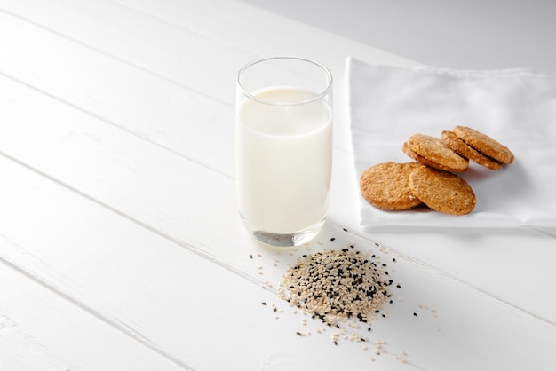 Cibo alternativo vegano al sesamo latte non caseario con biscotti su sfondo bianco in legno spazio copia