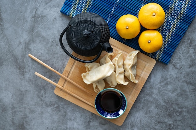 Cibo asiatico Dim sum con salsa di soia su tavola di bambù decorata con arance e teiera Copia spazio