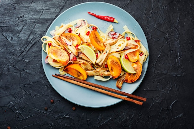 Cibo asiatico, insalata con pasta, cachi e melanzane.