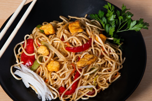 Cibo asiatico, tagliatelle yakisoba fritte con pollo. Immagine isolata.