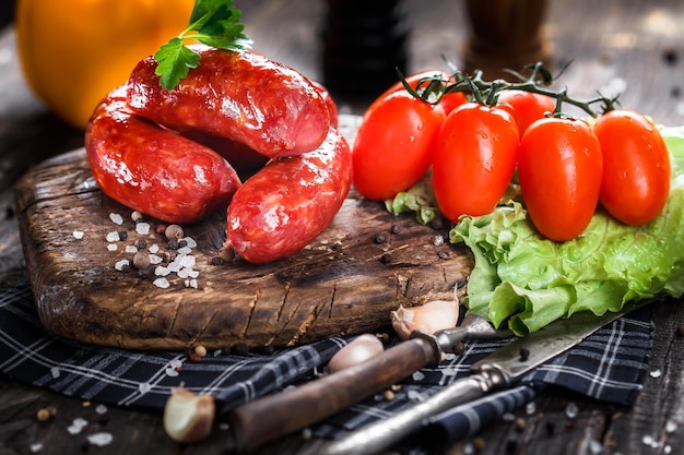 Cibo casereccio, salsiccia grossa fritta in padella, pomodorini e lattuga, spezie, fondente e lunatico