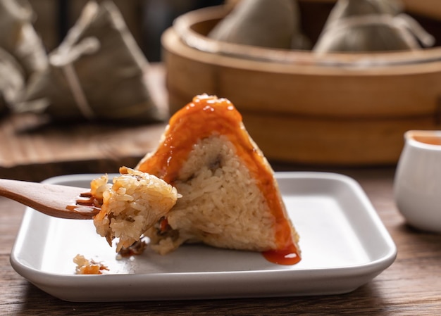 Cibo del Dragon Boat Festival Gnocco di riso zongzi giovane donna asiatica che mangia cibo tradizionale cinese su un tavolo di legno a casa celebrazione da vicino