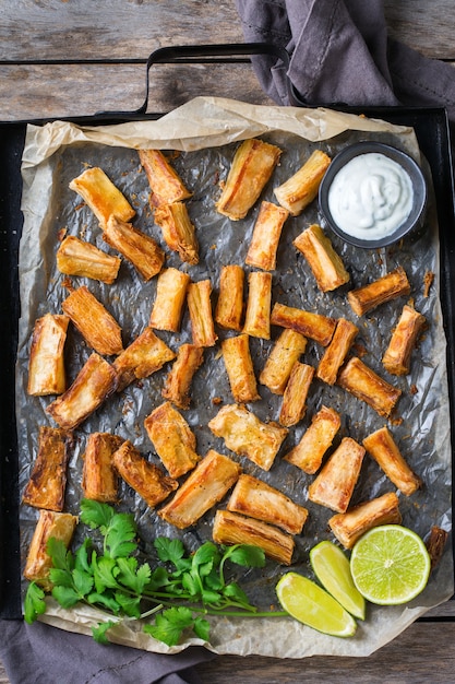 Cibo della cucina brasiliana, spuntino latino. Yucca fritta, yuca, manioca, bastoncini di manioca con salsa di coriandolo. Sfondo piatto vista dall'alto