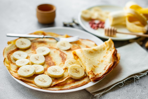 Cibo, dessert, pasticcini, frittelle, torta. Gustosi pancake con banana e miele su uno sfondo concreto