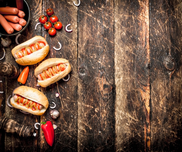 Cibo di strada. Hot dog freschi con peperoni, cipolle e pomodori sulla tavola di legno.