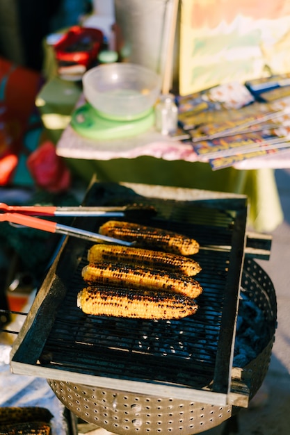 Cibo di strada lo chef griglia le pannocchie di mais