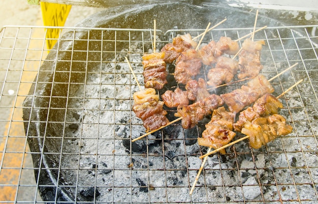 Cibo di strada. Spina di maiale alla griglia in legno o spiedini di maiale arrostiti sul fornello