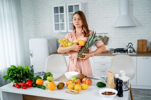 Cibo dietetico sano in cucina. Frutta e verdura sdraiata sul tavolo. Bella donna con cibo sano.