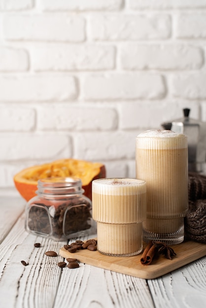 Cibo e bevande autunnali. Bevande di mare. Latte speziato di zucca con panna e spezie, vista frontale, sfondo muro di mattoni bianchi