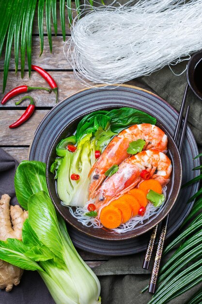 Cibo e bevande cucina tradizionale asiatica Zuppa piccante di bee hoon bihun con gamberetti gamberetti choy e riso vermicelli noodles su un tavolo di legno Vista dall'alto piatto laico sfondo