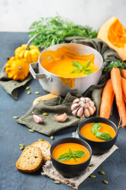 Cibo e bevande natura morta dieta e concetto di nutrizione Autunno stagionale autunno arrosto arancione zucca zuppa di carote con ingredienti su un rustico tavolo in legno Accogliente cucina sullo sfondo