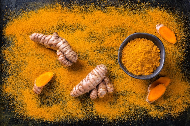 Cibo e bevande, nutrizione dietetica, concetto di assistenza sanitaria. Radice di curcuma arancione organica cruda e polvere, curcuma longa su un tavolo da cucina. Spezie orientali indiane a basso contenuto di colesterolo