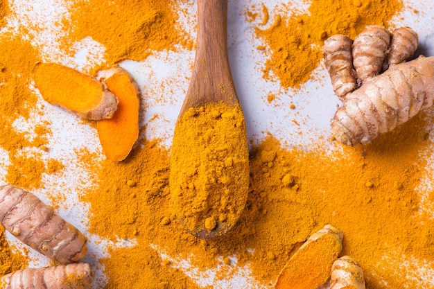 Cibo e bevande, nutrizione dietetica, concetto di assistenza sanitaria. Radice di curcuma arancione organica cruda e polvere, curcuma longa su un tavolo da cucina. Spezie orientali indiane a basso contenuto di colesterolo.