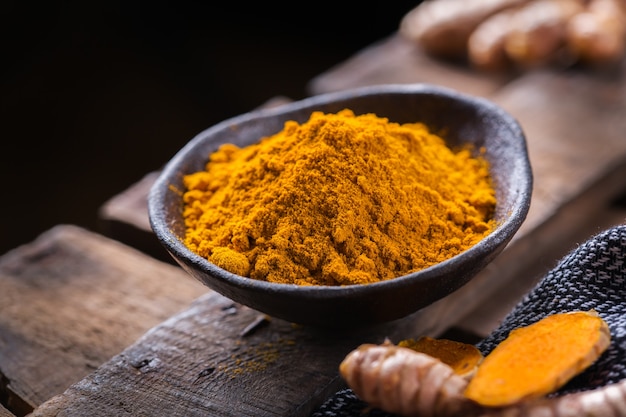 Cibo e bevande, nutrizione dietetica, concetto di assistenza sanitaria. Radice di curcuma arancione organica cruda e polvere, curcuma longa su un tavolo da cucina. Spezie orientali indiane a basso contenuto di colesterolo