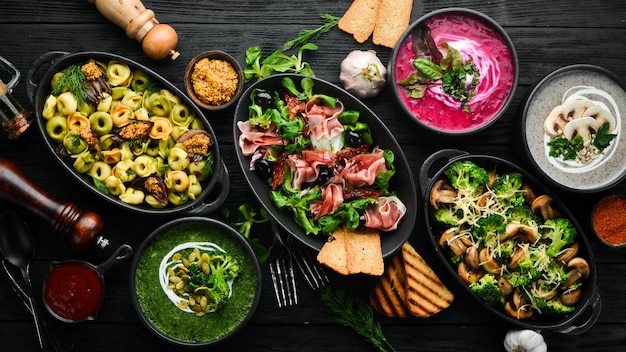 Cibo e piatti di sfondo Insalate, snack e zuppe su sfondo nero Vista dall'alto