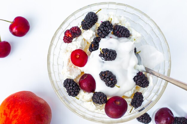 Cibo estivo. Una ciotola con ricotta e ciliegie e gelsi succose mature, crema di cocco. Un dolce sano e gustoso.