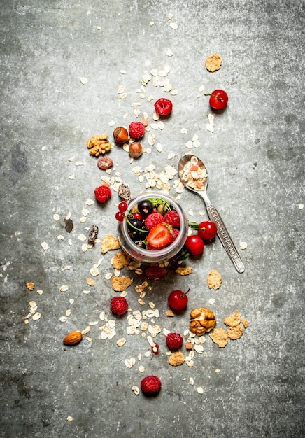 Cibo fitness. Bacche con muesli e noci sul tavolo di pietra.