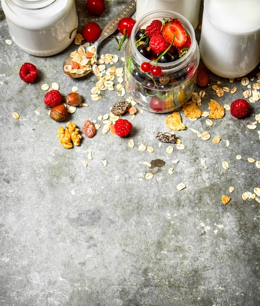 Cibo fitness. Muesli con frutti di bosco, noci e latte in bottiglia. Sul tavolo di pietra.