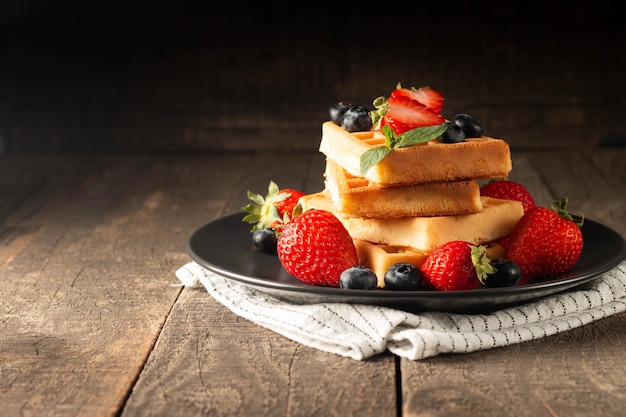 Cibo fresco fatto in casa di waffle belgi ai frutti di bosco con mirtillo alla fragola e cioccolato al miele