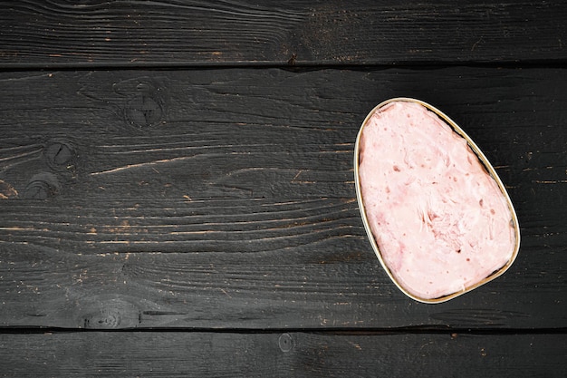 Cibo in scatola, set di prosciutto di carne per pranzo, su sfondo di tavolo in legno nero, vista dall'alto piatta, con spazio di copia per il testo