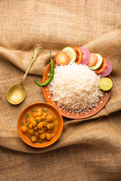 Cibo indiano chole chawal o curry piccante di ceci con riso semplice servito con insalata verde. messa a fuoco selettiva