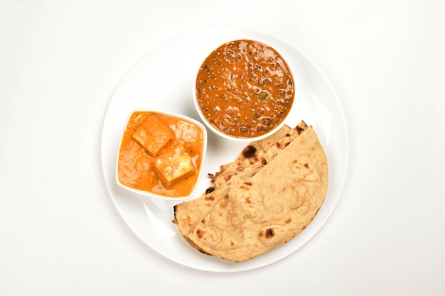 Cibo indiano nel piatto isolato su sfondo bianco Shahi Paneer con Dal Makhani e Tandoori Roti