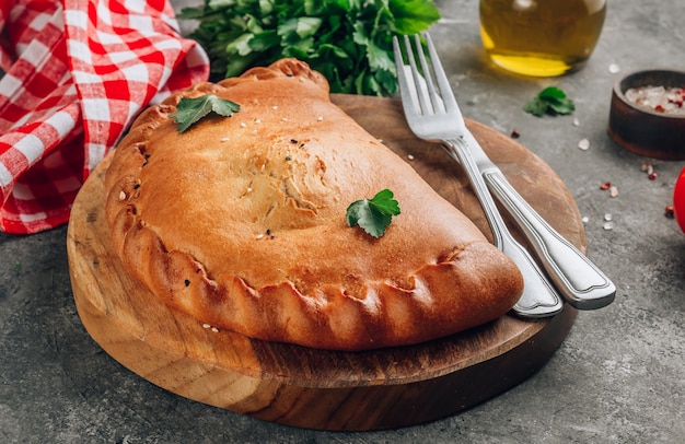 Cibo italiano, calzone chiuso pizza con formaggio, sfondo grigio pietra.