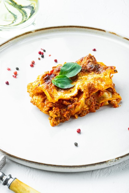 Cibo italiano. Set di lasagne calde gustose appena sfornate, su piastra, su fondo di pietra bianca