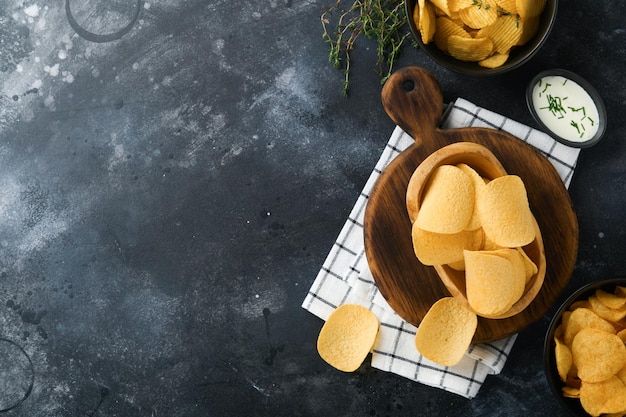 Cibo malsano Snack Tutti i classici snack di patate con popcorn alle arachidi e anelli di cipolla e salatini salati in piatti di ciotola su fondo di cemento nero Cibo malsano per i denti della pelle del cuore della figura