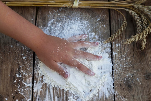 cibo natura morta con bambino che prepara a mano la farina di frumento per la cottura sul tavolo