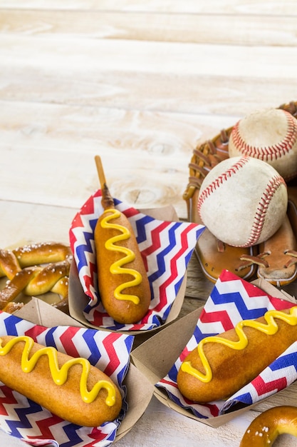 Cibo per feste di baseball con palline e guanti su un tavolo di legno.