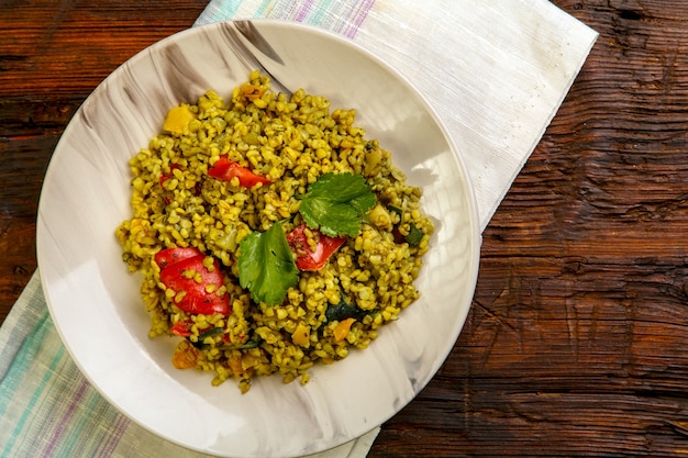 Cibo per suhoor in Ramadan bulgur post con verdure in un piatto su un tavolo di legno su un tovagliolo. Foto orizzontale