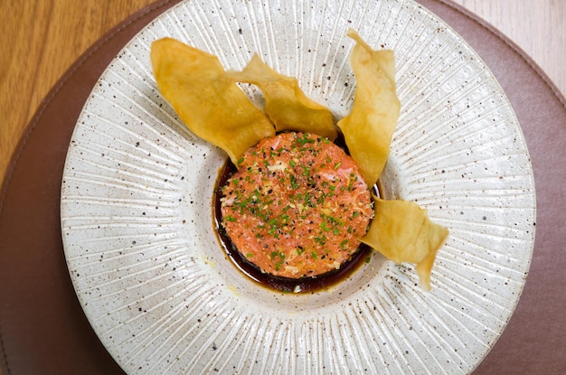 CIBO PERUVIANO Ceviche di salmone speziato con erba cipollina e lime su un piatto bianco servito con patate dolci fritte