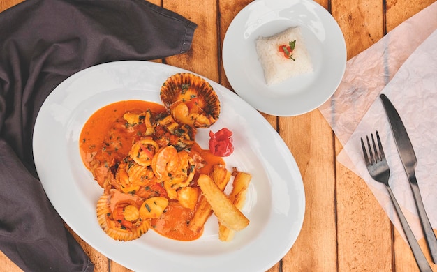 Cibo peruviano Piatto a lo macho tavolo di legno di pesce servito su un piatto bianco Pesce fritto in frutti di mare