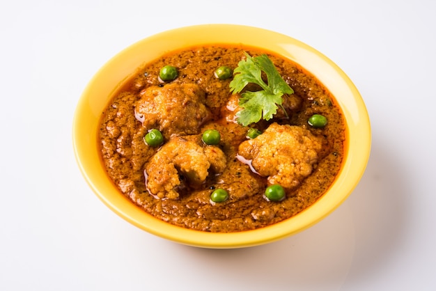 Cibo piccante indiano Gobi Masala o curry di cavolfiore con piselli verdi, servito in una ciotola di ceramica, fuoco selettivo