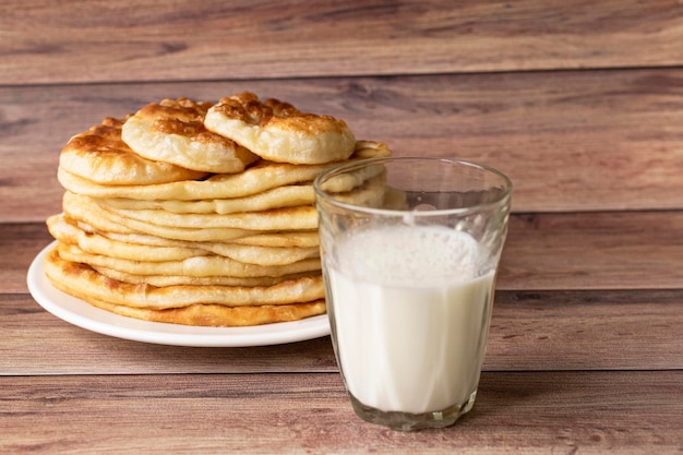 Cibo rustico sano Latte in bottiglia un bicchiere e torte calde per colazione Dolci di farina di frumento Sfondo di legno